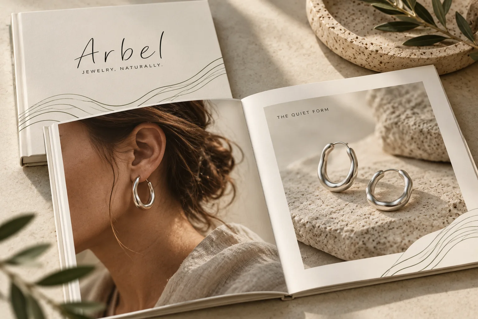 ספר קולקציה פתוח של Arbel: צילום תקריב של עגיל חישוק על אוזן, ומולו זוג עגילים על אבן.