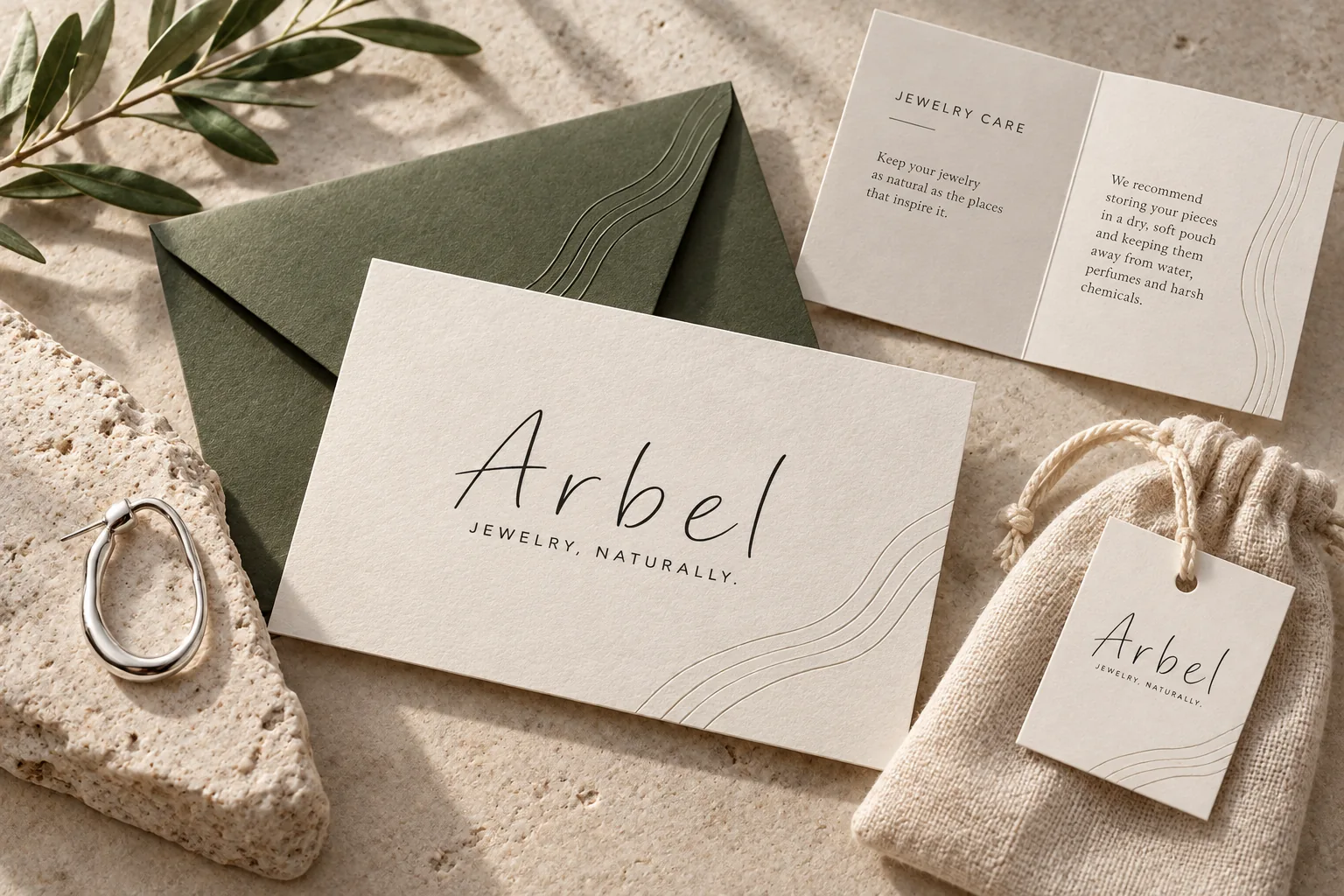 כרטיס Arbel עם מעטפה בזית, כרטיס טיפול בתכשיט ושקיק בד עם תווית.